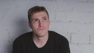 Siyah bir tişört, bir gri tuğla duvara yakışıklı bir adam. Acımasız adam dövme olan