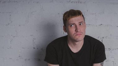 Siyah bir tişört, bir gri tuğla duvara yakışıklı bir adam. Acımasız adam dövme olan