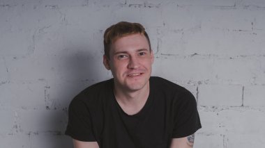 Siyah bir tişört, bir gri tuğla duvara yakışıklı bir adam. Acımasız adam dövme olan