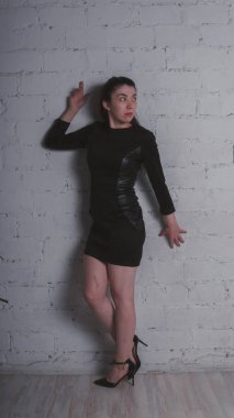 Kız beyaz duvara karşı poz. Siyah elbise modeli. Esmer Doğu görünüyor.