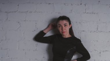 Kız beyaz duvara karşı poz. Siyah elbise modeli. Esmer Doğu görünüyor.