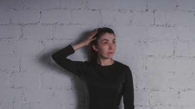 Kız beyaz duvara karşı poz. Siyah elbise modeli. Esmer Doğu görünüyor.