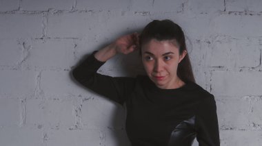 Kız beyaz duvara karşı poz. Siyah elbise modeli. Esmer Doğu görünüyor.