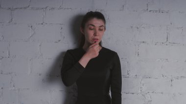 Kız beyaz duvara karşı poz. Siyah elbise modeli. Esmer Doğu görünüyor.