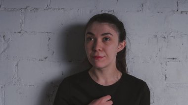 Kız beyaz duvara karşı poz. Siyah elbise modeli. Esmer Doğu görünüyor.