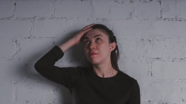 Kız beyaz duvara karşı poz. Siyah elbise modeli. Esmer Doğu görünüyor.