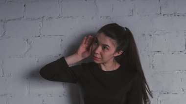 Kız beyaz duvara karşı poz. Siyah elbise modeli. Esmer Doğu görünüyor.