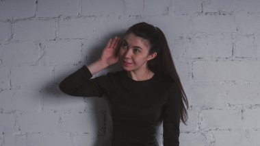 Kız beyaz duvara karşı poz. Siyah elbise modeli. Esmer Doğu görünüyor.