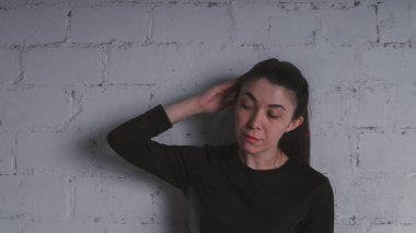 Kız beyaz duvara karşı poz. Siyah elbise modeli. Esmer Doğu görünüyor.