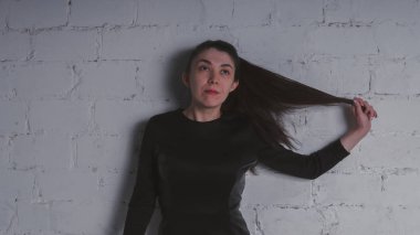 Kız beyaz duvara karşı poz. Siyah elbise modeli. Esmer Doğu görünüyor.