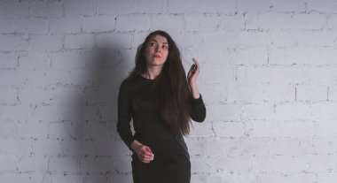 Kız beyaz duvara karşı poz. Siyah elbise modeli. Esmer Doğu görünüyor.