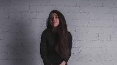Kız beyaz duvara karşı poz. Siyah elbise modeli. Esmer Doğu görünüyor.
