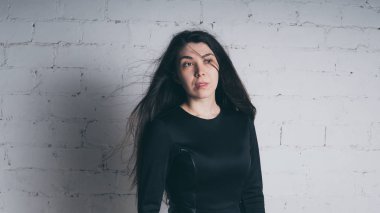 Kız beyaz duvara karşı poz. Siyah elbise modeli. Esmer Doğu görünüyor.