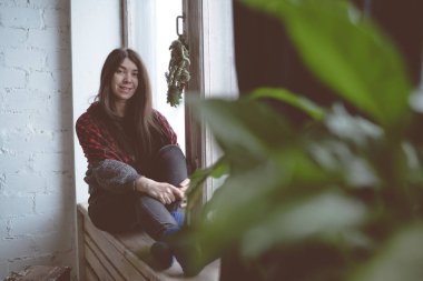 Pencerede, bir öğrenci bir gri süveterli oturan kız. Model pencereye poz. Konsept: romantizm ve özlem