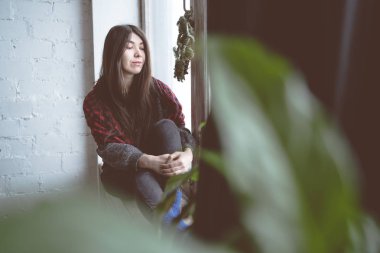 Pencerede, bir öğrenci bir gri süveterli oturan kız. Model pencereye poz. Konsept: romantizm ve özlem