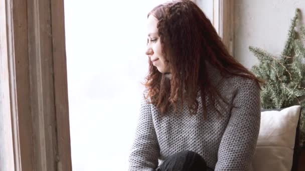 悲しみと人々 の概念 は冬ウィンドウ敷居自宅に座ってセーターの女の子のクローズ アップ — ストック動画