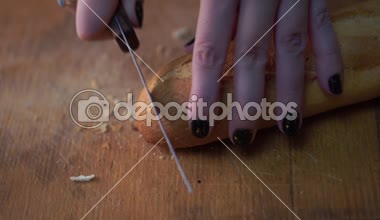 Baget Doğrama tahtası üzerinde yavaş, çok yavaş dilimleme. Beyaz ekmek kesme. Baget masaya dilimleme. Baget geleneksel Fransız ekmeği tablo kesme yakın çekim üzerinde. 