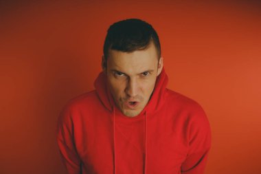 Turuncu bir arka plan üzerinde poz çılgın ve karizmatik adam. Bir erkekte bir kırmızı eşofman.