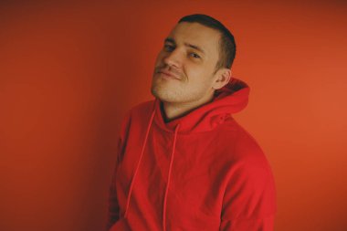 Turuncu bir arka plan üzerinde poz çılgın ve karizmatik adam. Bir erkekte bir kırmızı eşofman.