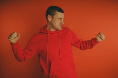 Turuncu bir arka plan üzerinde poz çılgın ve karizmatik adam. Bir erkekte bir kırmızı eşofman.