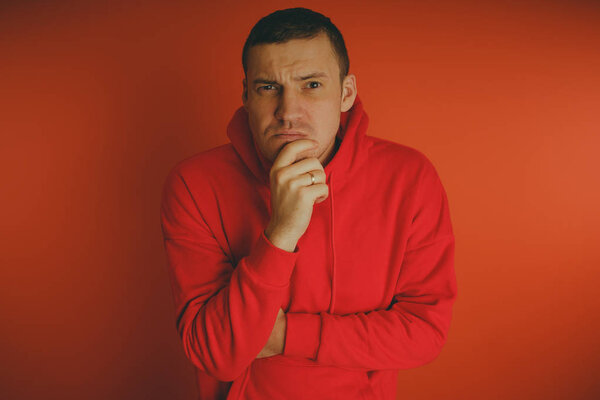 Crazy and charismatic guy posing on an orange background. A man in a red tracksuit.
