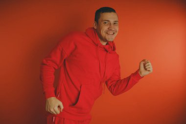 Turuncu bir arka plan üzerinde poz çılgın ve karizmatik adam. Bir erkekte bir kırmızı eşofman.