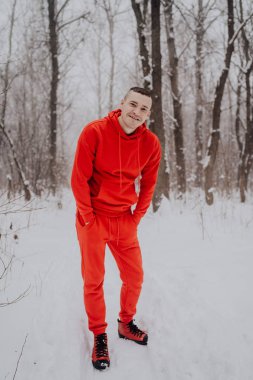 Deli adam ormanda kış kar ve ağaçlar arka plan üzerinde poz. Bir erkekte temiz havada yürüyüş bir kırmızı eşofman. Konsept: yürüyüş ve açık havada soğukta eğitim