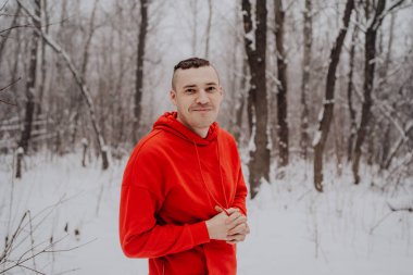 Deli adam ormanda kış kar ve ağaçlar arka plan üzerinde poz. Bir erkekte temiz havada yürüyüş bir kırmızı eşofman. Konsept: yürüyüş ve açık havada soğukta eğitim