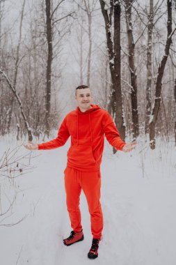 Deli adam ormanda kış kar ve ağaçlar arka plan üzerinde poz. Bir erkekte temiz havada yürüyüş bir kırmızı eşofman. Konsept: yürüyüş ve açık havada soğukta eğitim
