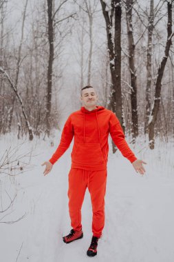 Deli adam ormanda kış kar ve ağaçlar arka plan üzerinde poz. Bir erkekte temiz havada yürüyüş bir kırmızı eşofman. Konsept: yürüyüş ve açık havada soğukta eğitim