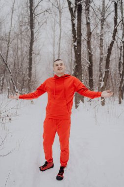 Deli adam ormanda kış kar ve ağaçlar arka plan üzerinde poz. Bir erkekte temiz havada yürüyüş bir kırmızı eşofman. Konsept: yürüyüş ve açık havada soğukta eğitim