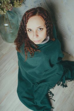 Kız katta oturan bir battaniyeye sarılmış. kavram: üzüntü, üzüntü ve melankoli