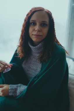 Kız katta oturan bir battaniyeye sarılmış. kavram: üzüntü, üzüntü ve melankoli