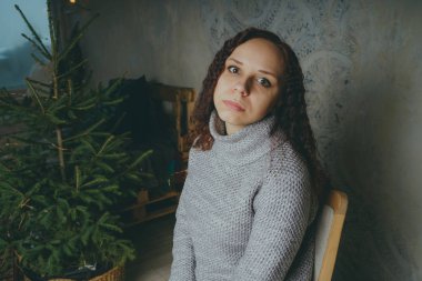 Gri bir duvara poz bir kazak bir genç kız. Sıcak kazak giymiş kadın sokak stil giyim. Temiz cilt, uzun saç