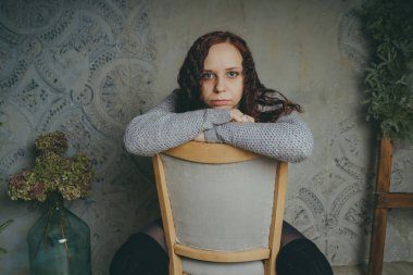 Gri bir duvara poz bir kazak bir genç kız. Sıcak kazak giymiş kadın sokak stil giyim. Temiz cilt, uzun saç