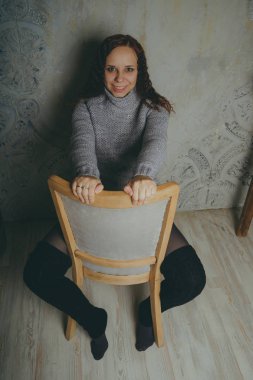 Gri bir duvara poz bir kazak bir genç kız. Sıcak kazak giymiş kadın sokak stil giyim. Temiz cilt, uzun saç