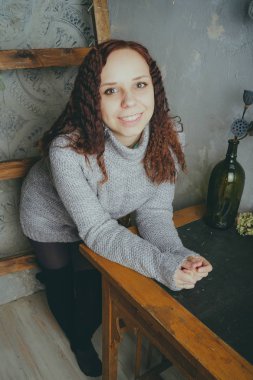 Gri bir duvara poz bir kazak bir genç kız. Sıcak kazak giymiş kadın sokak stil giyim. Temiz cilt, uzun saç