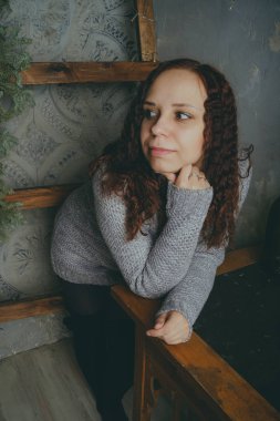 Gri bir duvara poz bir kazak bir genç kız. Sıcak kazak giymiş kadın sokak stil giyim. Temiz cilt, uzun saç