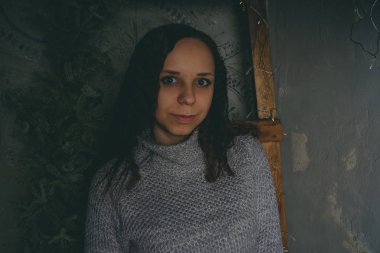 Gri bir duvara poz bir kazak bir genç kız. Sıcak kazak giymiş kadın sokak stil giyim. Temiz cilt, uzun saç