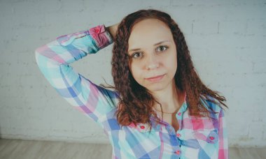 Deli kız beyaz bir duvar önünde poz. Sokak tarzı giyim: gömlek ve kot pantolon.