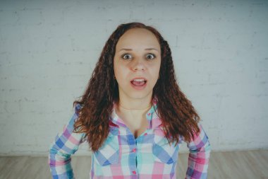 Deli kız beyaz bir duvar önünde poz. Sokak tarzı giyim: gömlek ve kot pantolon.