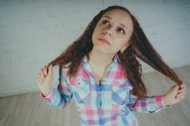 Deli kız beyaz bir duvar önünde poz. Sokak tarzı giyim: gömlek ve kot pantolon.