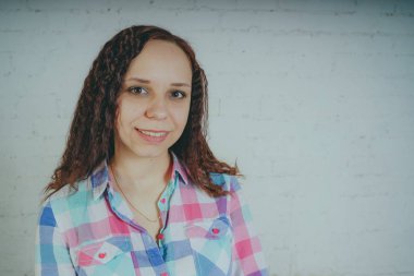 Deli kız beyaz bir duvar önünde poz. Sokak tarzı giyim: gömlek ve kot pantolon.