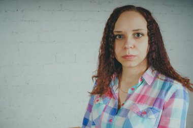 Deli kız beyaz bir duvar önünde poz. Sokak tarzı giyim: gömlek ve kot pantolon.