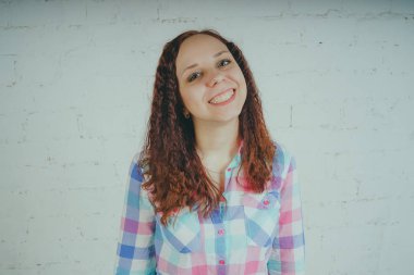 Deli kız beyaz bir duvar önünde poz. Sokak tarzı giyim: gömlek ve kot pantolon.