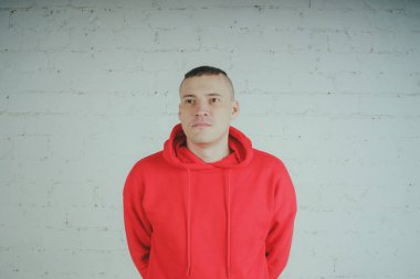 Yakışıklı olan bir tuğla duvar tarafından poz. Kırmızı kapüşonlu deli adam