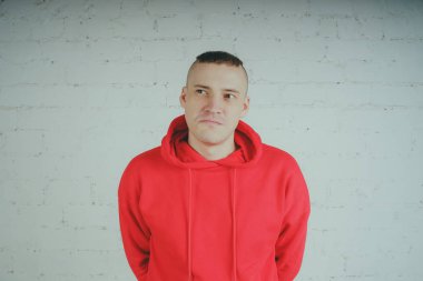 Yakışıklı olan bir tuğla duvar tarafından poz. Kırmızı kapüşonlu deli adam