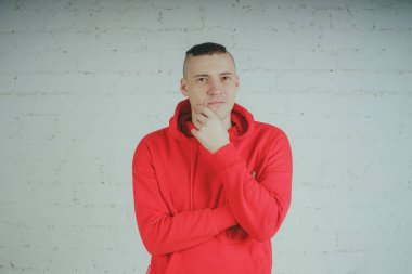 Yakışıklı olan bir tuğla duvar tarafından poz. Kırmızı kapüşonlu deli adam