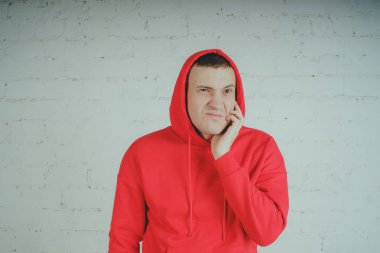 Yakışıklı olan bir tuğla duvar tarafından poz. Kırmızı kapüşonlu deli adam