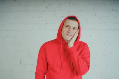 Yakışıklı olan bir tuğla duvar tarafından poz. Kırmızı kapüşonlu deli adam